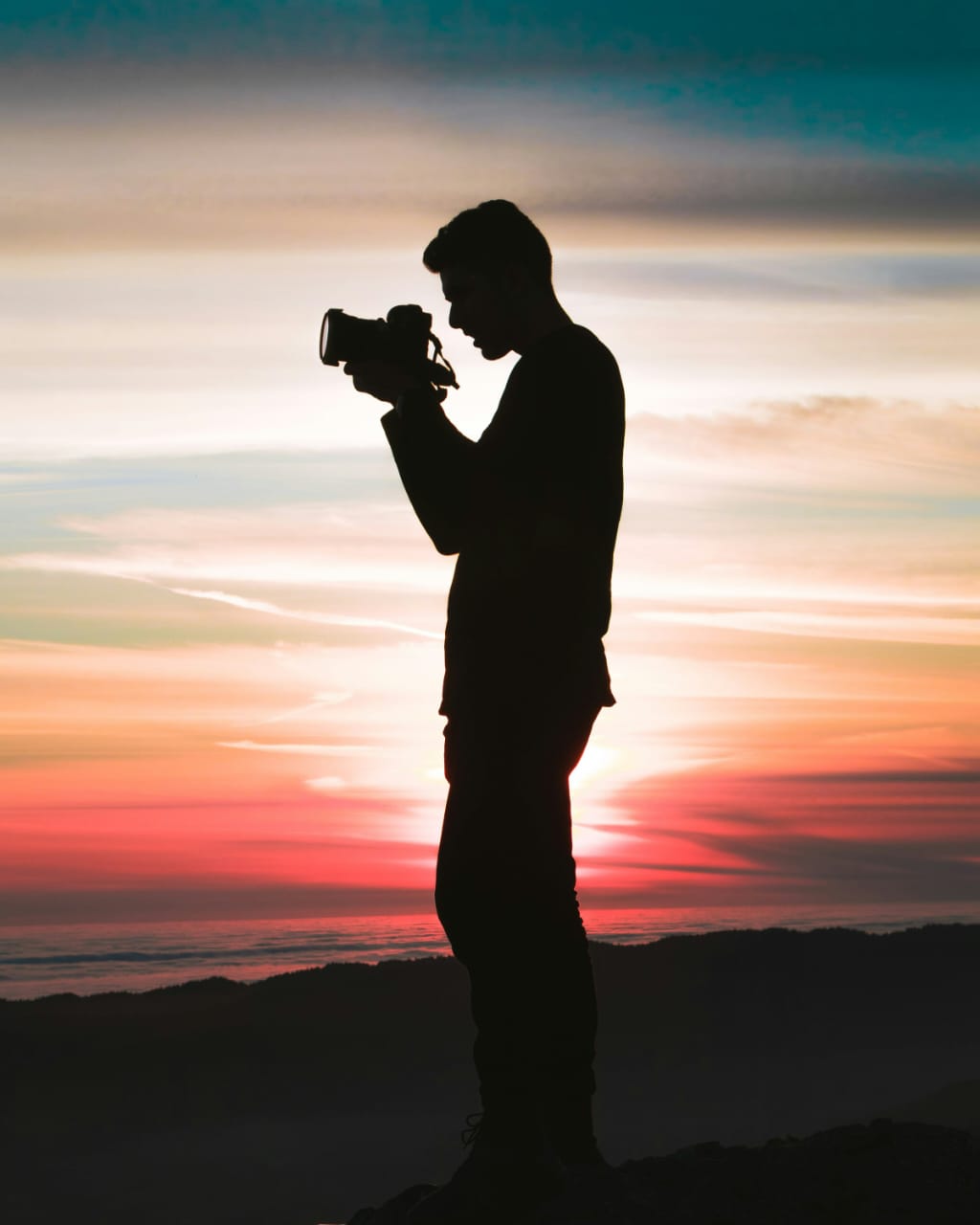 Silhueta fotografando ao pôr do sol